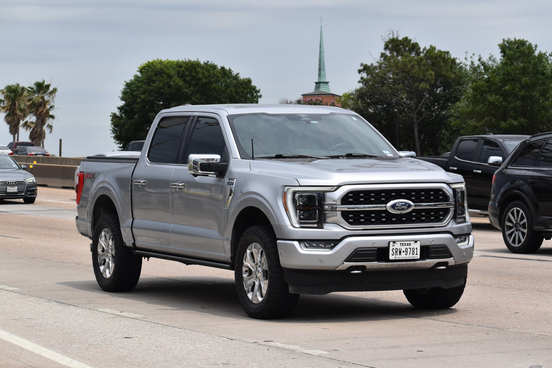 A portrait of a gray Ford F-150 pick-up truck traveling down a highway in moderate traffic