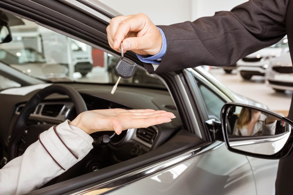 man handing a car key to a woman