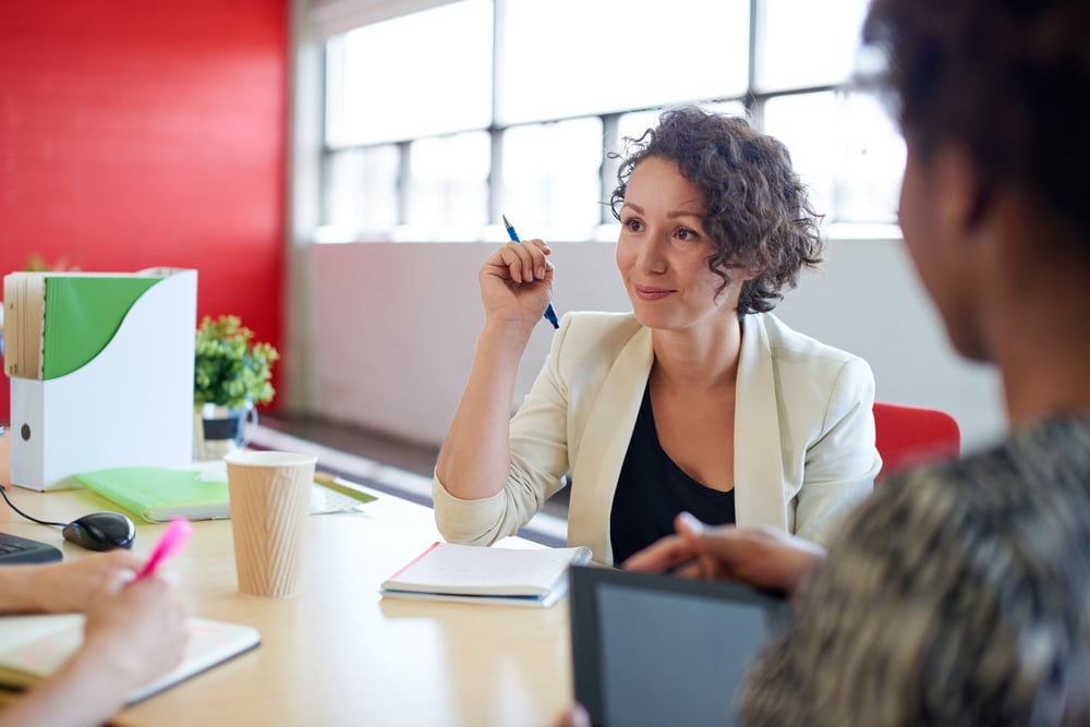 woman at desk holding pen in a meeting